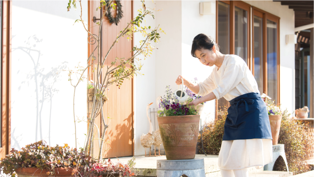 配偶者居住権の記事入りイメージ画像、玄関で主婦がお花の手入れをしている